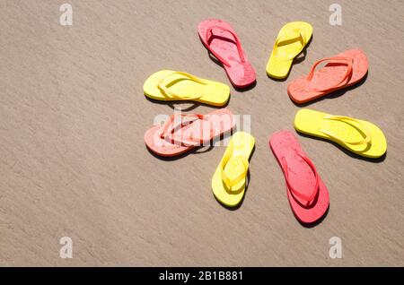 Sonniger Flip-Flops-Kreis in hellen Farben am glatten Sandstrand Stockfoto
