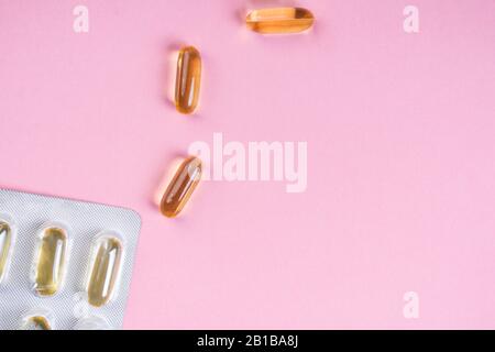 Gelbe Ölkapseln auf pinkfarbenem Hintergrund, Vitamine und Antioxidanskonzept Omega 3, Lebercod oder Abend-Primosöl für die Gesundheit. Minimalismus. Kopierbereich. Stockfoto