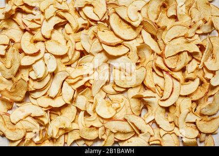 Apfelspäne auf der gesamten Tischoberfläche. Vegetarische Ernährung. Getrocknete apfelscheiben. Nützliches Essen. Rohkost. Stockfoto