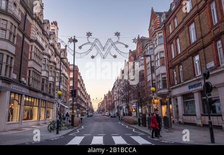 Zwei Personen, die die Straße in der New Cavendish Street, Marylebone, London, W1 überqueren. Stockfoto