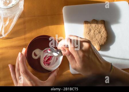 Kochplätzchen: Farbmittel mit Glasur mischen, um an einem sonnigen Nachmittag zu Hause ein hausgemachtes Blumenplätzchen zu schmücken. Stockfoto