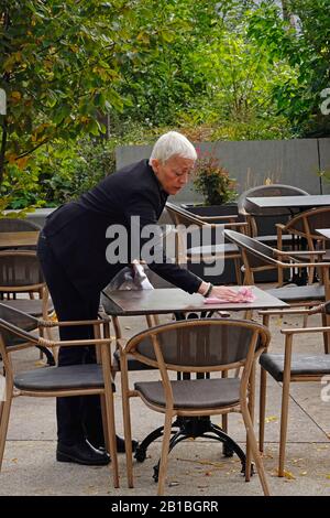 Frau Reinigung Tische im Café vor Service in Paris Frankreich Stockfoto