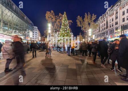 Budapest, Ungarn - 30. November 2019: Menschen auf der Straße am Vorosmarty-Platz mit Weihnachts-Einkaufsmarkt am Abend in der Ferienzeit. Stockfoto