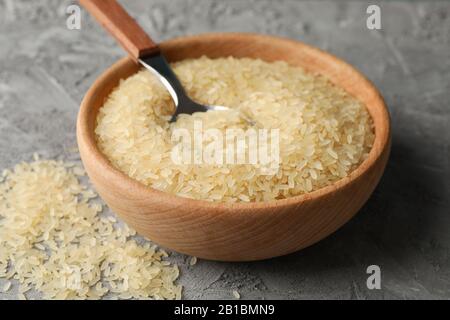 Schüssel mit Reis und Löffel auf grauem Hintergrund, Nahaufnahme Stockfoto