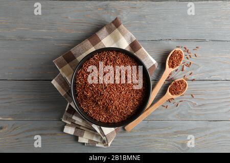 Schüssel mit Reis, Handtuch und Löffeln auf Holzhintergrund, Draufsicht Stockfoto