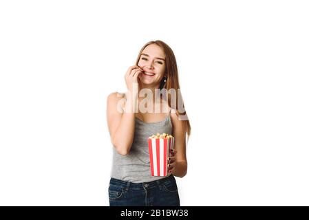 Mädchen im Studio mit Popcorn herumtören. Porträt eines lachenden Mädchens, das Popcorn hält und die Kamera über weißem Hintergrund isoliert betrachtet. Stockfoto