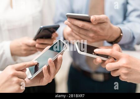 Gruppe junger Hipster, die das Telefon in den Händen halten. Freunde, die Spaß mit Smartphones haben. Stockfoto