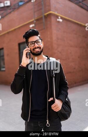 Reisen, Tourismus und Lifestyle Konzept - lächelnder Indischer Mann mit Rucksack Aufruf auf dem Smartphone auf Stadt. Stockfoto