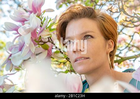 Porträt der jungen Frau in der Nähe der blühenden magnolie Stockfoto