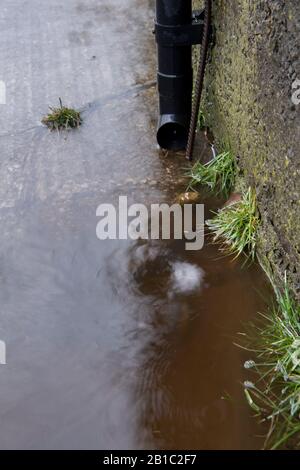 Schmutzwasser von einem Hof, der nach einem Sturm einen Abfluss abführt. North Yorkshire, Großbritannien. Stockfoto