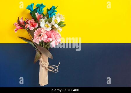 Ein Blumenstrauß mit einer leeren weißen Karte auf dem hellen Hintergrund. Draufsicht auf den Frühlings-Blumenhintergrund mit Platz für Kopien. Leerzeichen für Text ein Stockfoto