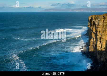 Große Wellen unter Klippen auf der westlichen Seite von Dunnet Head, Caithness, Schottland, Großbritannien. Die Insel Hoy, Orkney, in der Ferne. Stockfoto