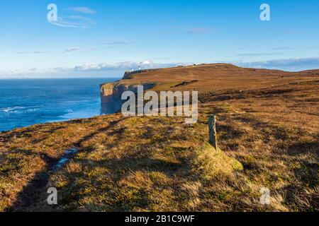 Die Strecke über den Klippen auf der westlichen Seite von Dunnet Head, Caithness, Schottland, Großbritannien, mit dem Leuchtturm in der Ferne. Stockfoto