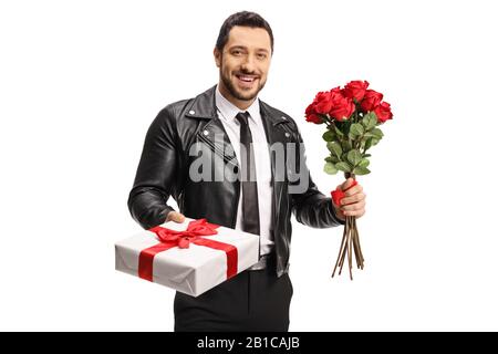 Mann in einer Lederjacke mit Geschenkbox und einem Haufen roter Rosen isoliert auf weißem Hintergrund Stockfoto