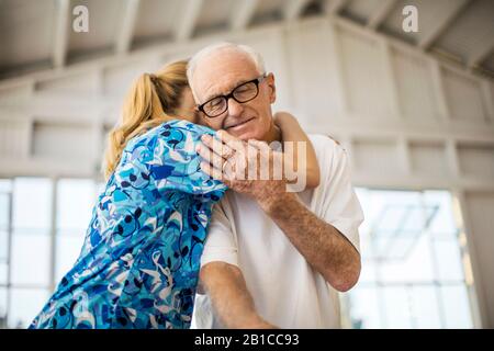 Die freundliche junge Pflegekraft umarmt einen älteren Patienten. Stockfoto