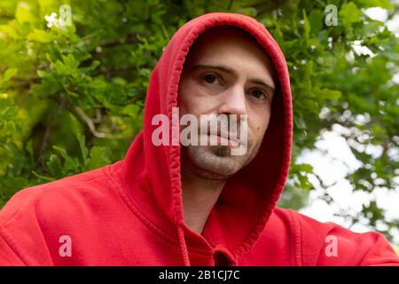 Portrait von jungen Mann mit Rot hoodie Suche wirklich ernste Stockfoto