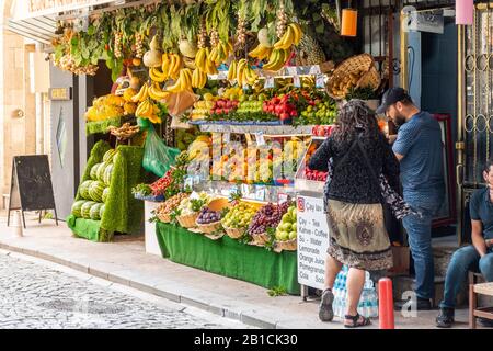 Eine Frau kauft frisches Obst von einem Straßenhändler, der in Istanbul, Türkei, Produkte und Säfte verkauft. Stockfoto