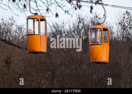 Gelb-orangefarbene Seilbahnkabinen im Winter. Vergnügungspark mit Spaß und Unterhaltung. Hoch in Bäumen, Ansicht schließen Stockfoto