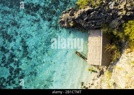 Blick von oben, atemberaubender Luftblick auf einen von felsigen Klippen umgebenen, von einem türkisfarbenen, kristallklaren Meer umgebenen, Urlaub. Stockfoto