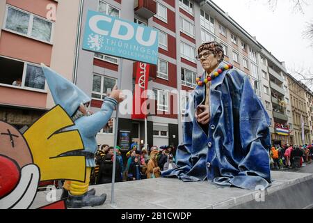 Mainz, Deutschland. Februar 2020. Die Vorsitzende der christlich-demokratischen Union (CDU) und Bundesverteidigungsministerin Annegret Kramp-Karrenbauer ist auf einer Floskel in der Mainzer Rosenmontagsparade abgebildet. Sie trägt ein überdimensionales Kleid von Bundeskanzlerin Angela Merkel und Zwerg mit einem STOPPSCHILD und einem Schild, das vor ihr "CDU Thüringen" liest, und lobt, dass sie Angela Merkels Schuhe nicht füllen kann, vor allem nach dem jüngsten Skandal nach der Thüringer Wahl. Rund eine halbe Million Menschen säumten die Straßen von Mainz für die traditionelle Rose Monday Carnival Parade. Die 9 km lange Parade Stockfoto