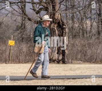 Lancaster County, Pennsylvania USA: 24. Februar 2020: Älterer Mann mit Gehstock, der einen warmen Wintertag genießt, während er im Park spazieren geht. Stockfoto