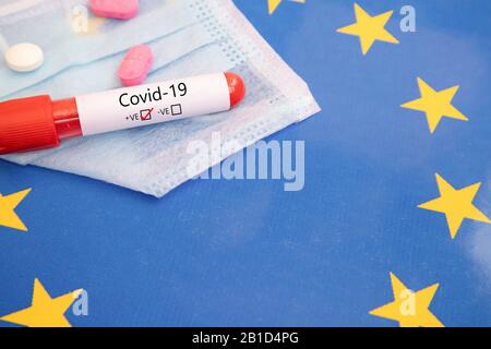 Konzept von Covid-19, Coronavirus oder nCov 2019 positiver Test auf Europa gefunden, der mit Blutprobe, medizinischer Maske, Tabletten und Flagge gezeigt wird. Stockfoto