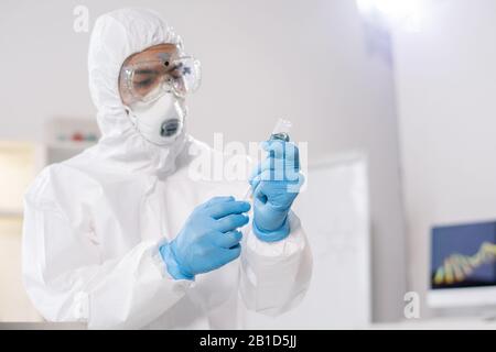 Arzt in Schutzkleidung, Schutzbrille und Atemschutzspritze beim Impfen mit Viren im medizinischen Zentrum Stockfoto