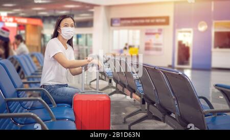 Asiatischer Tourist mit Gepäck, der hygienische Maske trägt, um während der Reisezeit am Flughafenterminal zum Schutz vor dem Coronavirus 2019 zu verhindern (COVID-1 Stockfoto