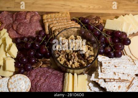 Essen von Charcuterie Board. Frisches Fleisch, Käse, Kräcker, Trauben und Honig auf einem Holztablett. Italienische Fingerfood-Vorspeise. Cl Stockfoto