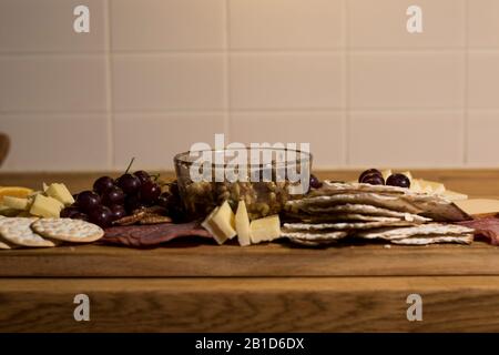 Sie essen Trauben, Walnüsse, Kräcker und Fleisch aus der Charcuterie. Nahaufnahme der Platte mit köstlichen Delikatessen, verschiedenen Snacks. Fleischscheiben und c Stockfoto