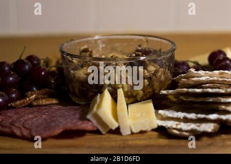 Essen Sie Fingerfood auf Holztablett mit Fleischkäse und Crackern. Eine Auswahl an Wurst und Käse, die auf einer Charcuterie-Tafel verzehrt werden können. Stockfoto