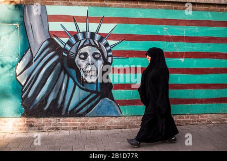 Frau spaziert vor anti-US-Wandbildern an den Wänden der ehemaligen US-Botschaft in Teheran Stockfoto