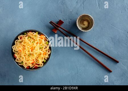 Sofort-Nudeln-Schüssel mit Karotten und Hengsten, Top-Schuss mit Essstäbchen und Sake Stockfoto