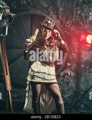 Steampunk-Frau mit mechanischer Pistole. Wunderschönes Mädchen, Modell im Stil eines Steampunks in einem schönen Kreativstudio. Mode, Stil Stockfoto