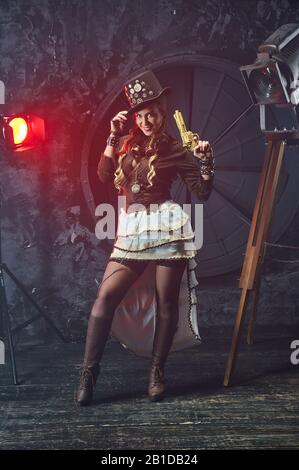 Steampunk-Frau mit mechanischer Pistole. Wunderschönes Mädchen, Modell im Stil eines Steampunks in einem schönen Kreativstudio. Mode, Stil Stockfoto