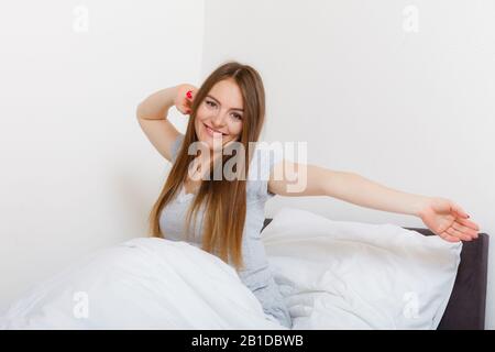 Morgen, kühlen Personen Konzept. Attraktive Frau im Bett. Schöne junge Dame hat gemütliche Schlafanzüge und lange Haare. Stockfoto