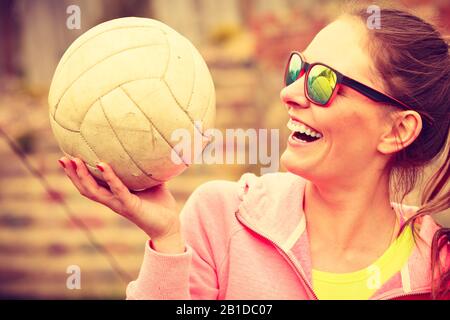 Sportspiele und Personenkonzept. Junge Frau in Sportbekleidung Sonnenbrille Volleyballerin hält Ball im Freien Stockfoto