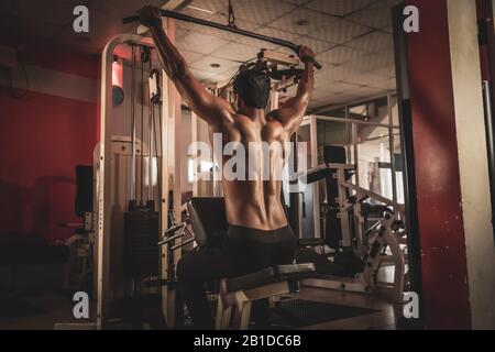 Fitness-Mann, der im Fitnessstudio ein Pulldown-Training ausarbeitet Stockfoto