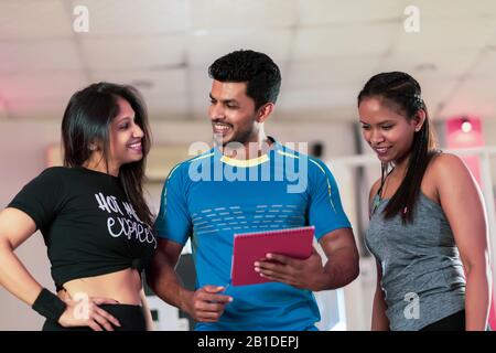 Stattliche personal trainer mit seinen Kunden im Fitnessstudio Stockfoto