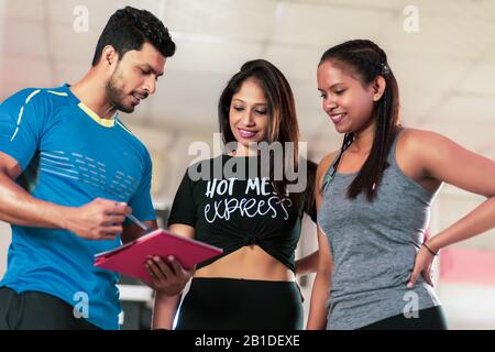 Stattliche personal trainer mit seinen Kunden im Fitnessstudio Stockfoto