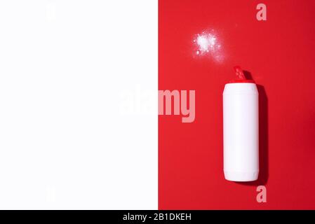 Weiße Kunststoffflasche mit Waschpulver oder Reinigungsmittel auf rotem Hintergrund. Kopierbereich. Draufsicht. Flaches Lay. Konzept für Haushaltschemikalien. Stockfoto