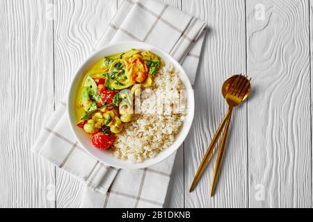Kokos- und Pilzkräuseln mit Champignons, frischem Spinat, Kirschtomaten serviert mit klebrigem Reis auf einem weißen Teller auf weißem Holzhintergrund, Hor Stockfoto