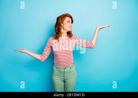 Portrait der positiven fröhlichen Frau Hold Hands Look entscheiden Sie, welche Werbung Promo-Auswahl suggerieren, dass Sie einen lässigen Pullover tragen, der über blaue Farben isoliert ist Stockfoto