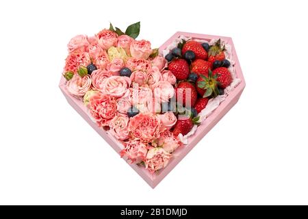 Holzkiste in Herzform mit Rosen und reifen Erdbeeren isoliert auf weißem Hintergrund. Stockfoto
