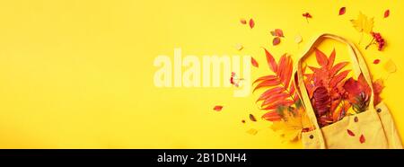 Herbst-Flachlaienzusammensetzung. Trockener Ahorn im Herbst in gelber Einkaufstasche auf gelbem Hintergrund. Draufsicht. Kopierbereich. Flaches Lay Stockfoto