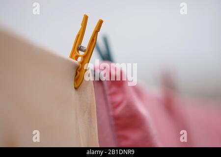 Die Kleidung wird im Freien an einem Seil mit Kunststoffkleidern getrocknet. Schöner selektiver Fokus. Stockfoto