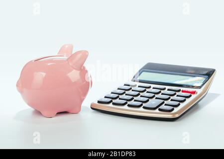 Piggy Bank mit Rechner auf weißem Hintergrund. Kreatives Foto. Stockfoto