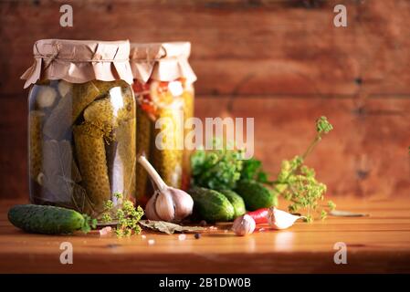 Eingepickte Gurken in Dosen über Holzhintergrund. Kopierbereich. Konserven oder fermentierte Lebensmittel. Harvest Preserve Konzept. Probiotische Lebensmittel. Stockfoto