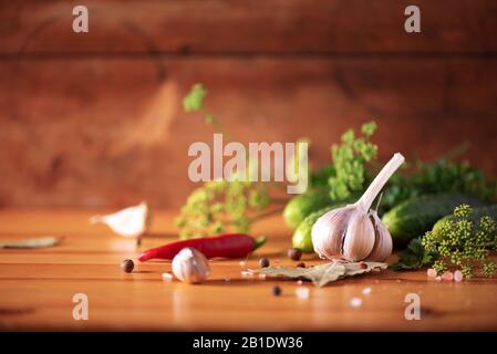 Gurken in Dosen beizen. Zutaten für marinierte Gherkins, Glasbecher, Knoblauch, Dill, Salz, Pfeffer auf grünem Hintergrund. Kopierbereich. Konzept der Gemüsekonservierung Stockfoto