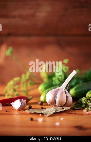 Gurken in Dosen beizen. Zutaten für marinierte Gherkins, Glasbecher, Knoblauch, Dill, Salz, Pfeffer auf grünem Hintergrund. Kopierbereich. Konzept der Gemüsekonservierung Stockfoto